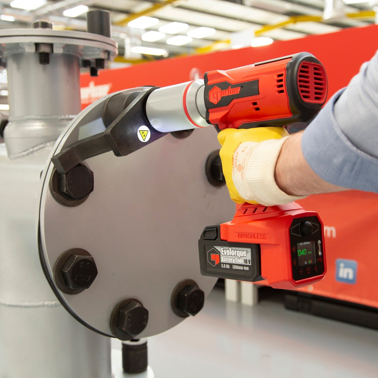 Person using a cordless drill on a mechanical component in an industrial setting